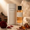 Oud Ispahan perfume bottle and cream cylindrical packaging beside oud wood, amber-colored resin and a red rose